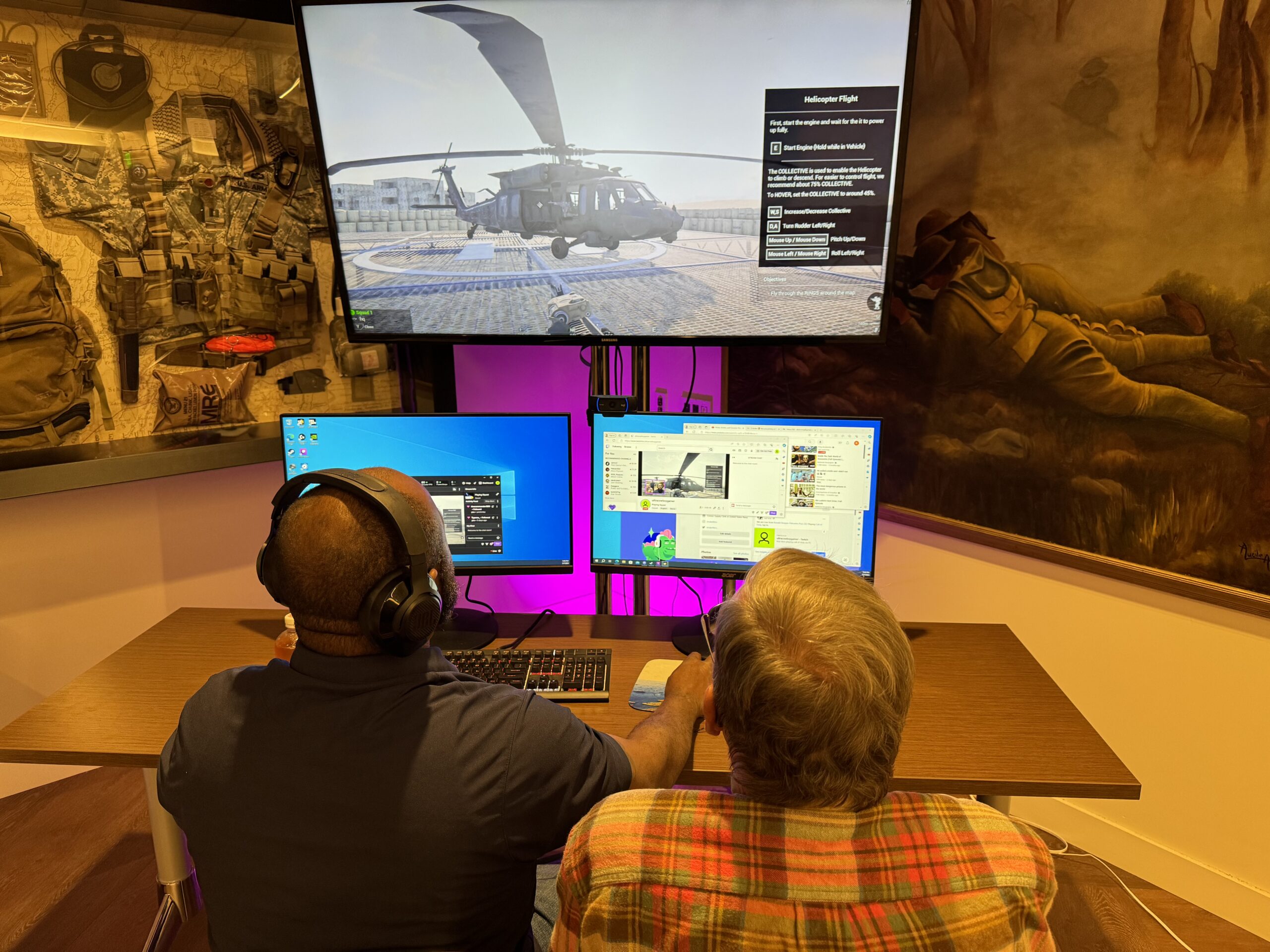 Iraq War veteran Andre Andrews, left, gears up to pilot a helicopter in the PC game Squad as Vietnam Huey pilot and Flying Cross recipient Dave Borgeson shares real-world cockpit stories at Post 283 in Pacific Palisades on May 7, 2024.